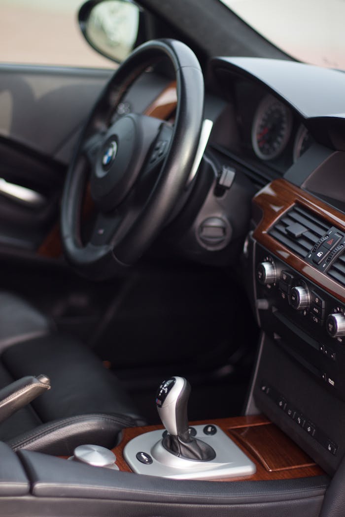 Close-up view of a luxury cars interior featuring a steering wheel, dashboard, and gearshift.